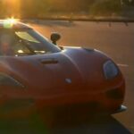 En man står bredvid en röd sportbil. (AI text)