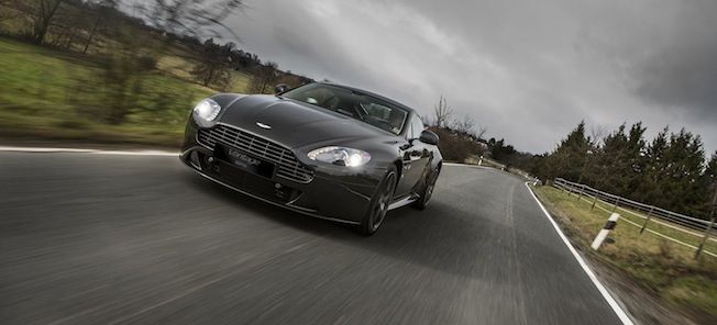 En Aston Martin Vantage kör nedför en landsväg. (AI text)