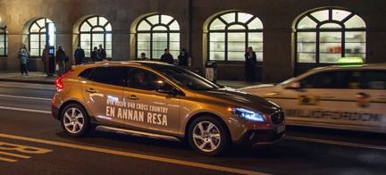 En bil kör fram på en stadsgata på natten. (AI text)