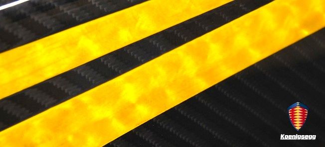 En gul och svart bil med en gul streck på sidan. (AI text)