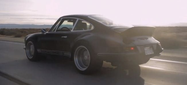 En svart Porsche 911 GTS kör längs en ökenväg. (AI text)