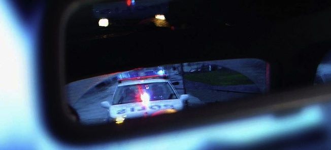 En polisbil återspeglad i en backspegel. (AI text)