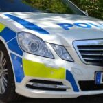 En polisbil parkerad vid en väg. (AI text)