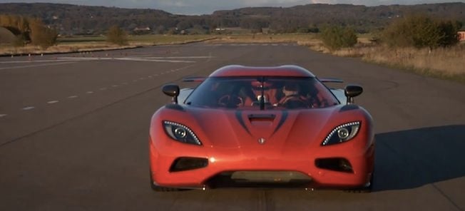 En röd sportbil kör nerför en väg. (AI text)