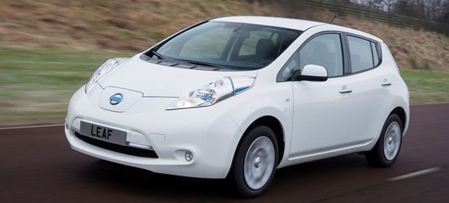 En vit Nissan Leaf kör nedför en landsväg. (AI text)
