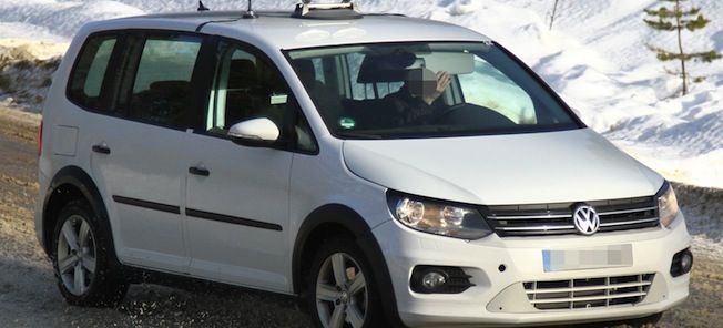 En vit Volkswagen cabriolet kör nerför en snöig väg. (AI text)