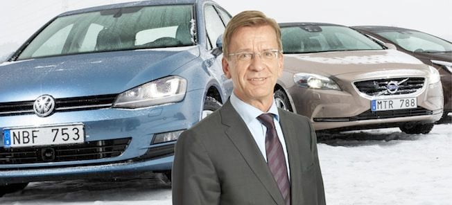 En man i kostym står bredvid en bil. (AI text)