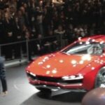 En man står bredvid en röd bil. (AI text)