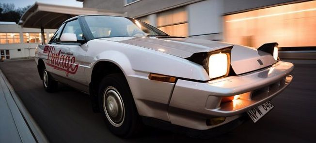 En sportbil kör nerför en gata. (AI text)