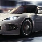 En vit sportbil kör nedför en stadsgata. (AI text)