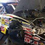 En racebil undersöks och repareras i en garage. (AI text)