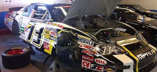 En racebil undersöks och repareras i en garage. (AI text)