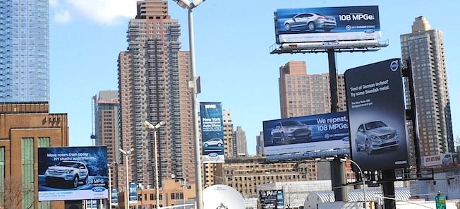 En stadsgata med mycket bilar och folk. (AI text)