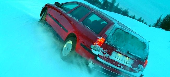 En röd bil kör nerför en snöig väg. (AI text)