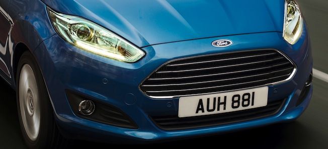 en blå Ford Fiesta kör nerför en väg (AI text)