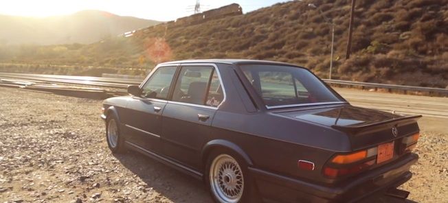 En BMW E30 parkerad på en grusväg. (AI text)