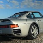 En silverfärgad Porsche 911 parkerad på en strand. (AI text)