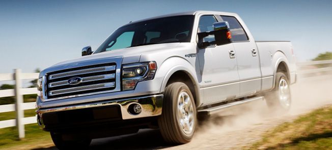 En vit Ford F-150 lastbil kör nedför en grusväg. (AI text)