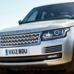 En silverfärgad Land Rover kör längs en grusväg. (AI text)