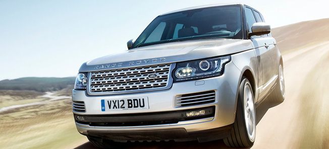 En silverfärgad Land Rover kör längs en grusväg. (AI text)