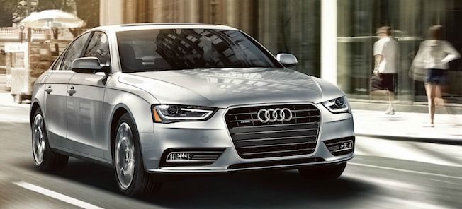 En silverfärgad Audi A4 kör nedför en stadsgata. (AI text)