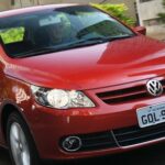 En röd Volkswagen Polo kör ner en gata. (AI text)