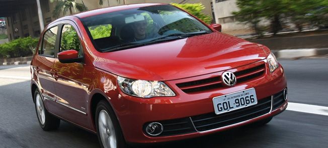 En röd Volkswagen Polo kör ner en gata. (AI text)