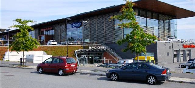 En bil parkerad framför ett byggnad. (AI text)