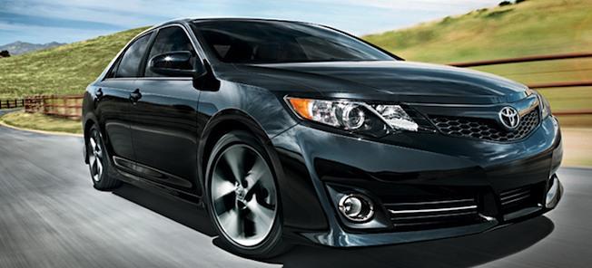 En svart Toyota Camry kör nerför en landsväg. (AI text)