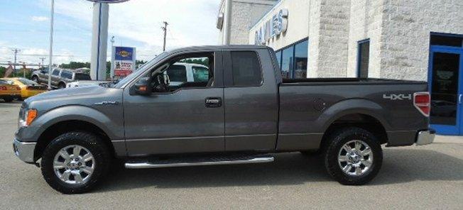 En grå Ford F-150 parkerad framför en bilhandel. (AI text)