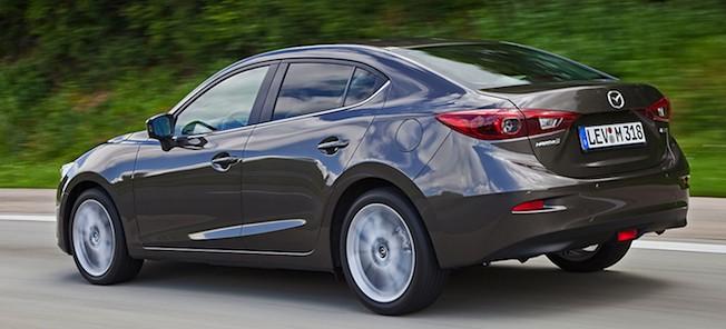 En Mazda3 skåp kör nedför en landsväg. (AI text)