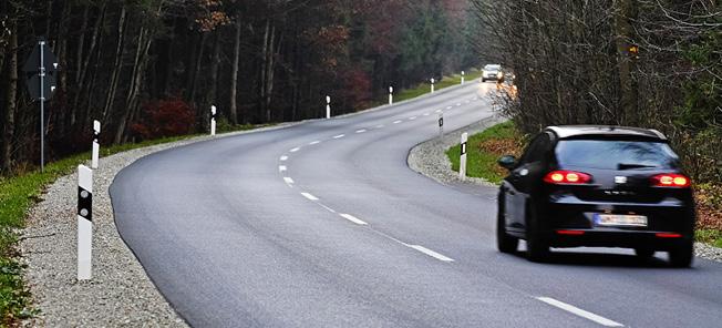 En bil kör genom en skogsväg. (AI text)