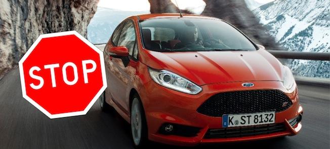 En Ford Fiesta kör nerför en bergsväg med en stoppskylt. (AI text)