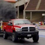 En röd Dodge-lastbil kör längs en dragslip. (AI text)