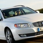 En vit Volvo V60 vagn kör nedför en landsväg. (AI text)