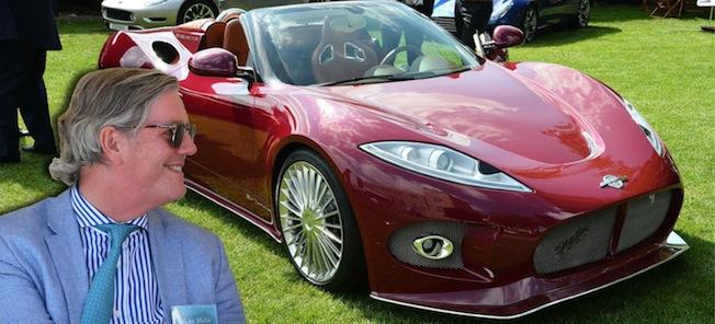 En man i kostym och slips står bredvid en röd sportbil. (AI text)