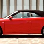 En Audi A3 Cabriolet parkerad framför ett byggnad. (AI text)