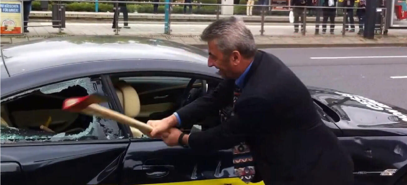 En man krossar en bilfönster med en hammare. (AI text)