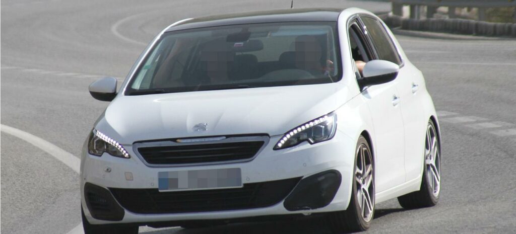 En vit bil kör nerför en väg. (AI text)