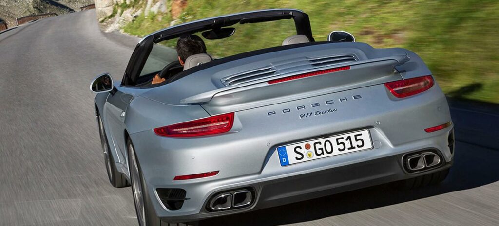 Porsche 911 cabriolet kör nedför en bergväg. (AI text)