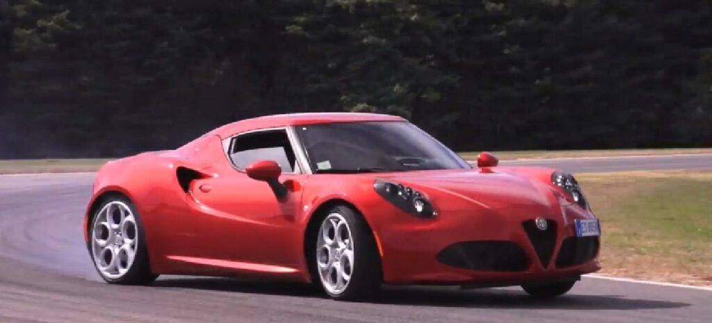 En röd Alfa Romeo sportbil kör på en bana. (AI text)