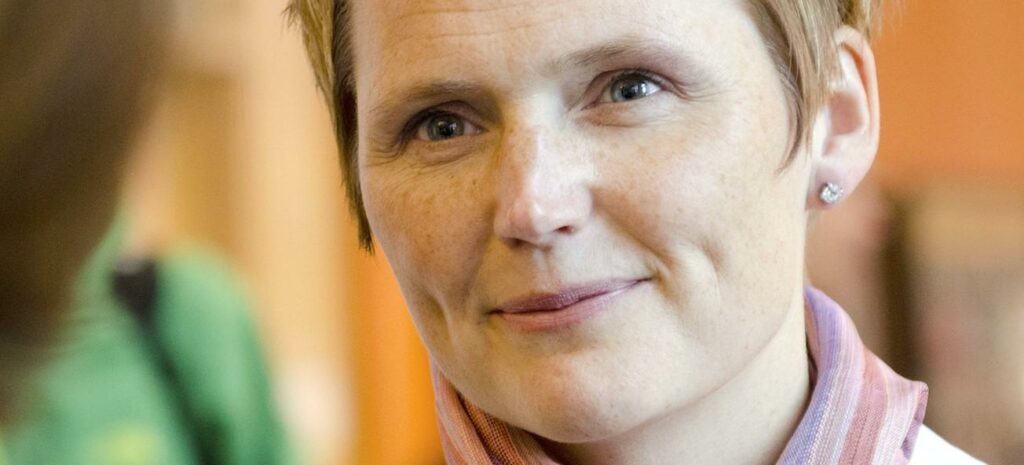 En kvinna talar med en man i laboratoriedräkt. (AI text)