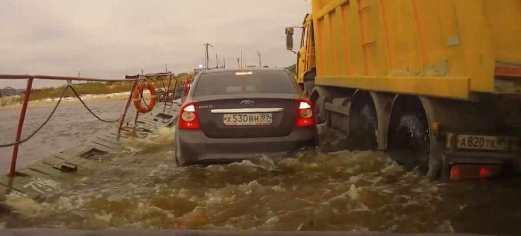 En bil är fast i en översvämning på en väg. (AI text)