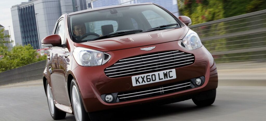 En röd bil kör nedför en stadsgata. (AI text)