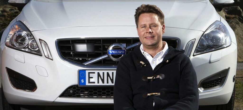 En man sitter framför en bil. (AI text)