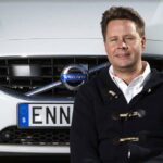 En man sitter framför en bil. (AI text)