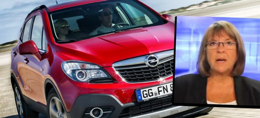 En kvinna står bredvid en röd bil. (AI text)