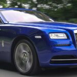 En blå Rolls-Royce kör nerför en landsväg. (AI text)