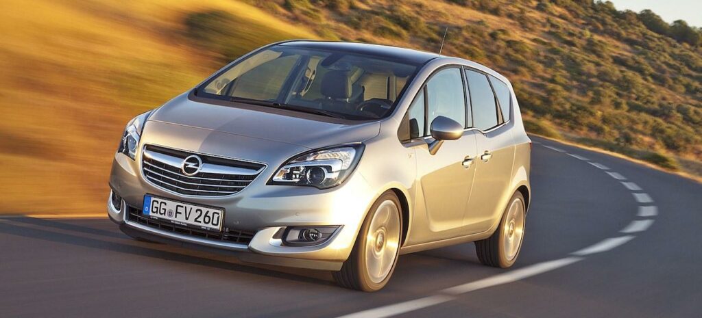 En silverfärgad bil kör nerför en väg. (AI text)