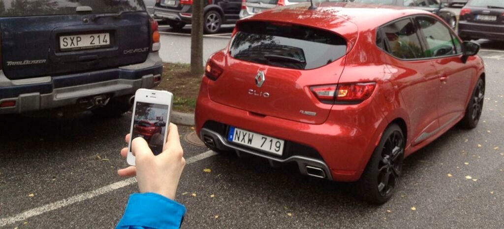 En person tar en bild av en bil. (AI text)